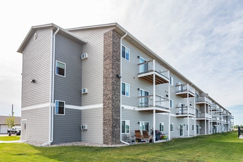 Apartment building with a grey siding and a brick pillar.